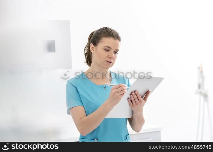 Doctor analyzing medical report on clipboard at dental clinic