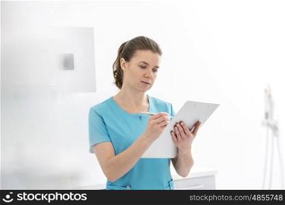 Doctor analyzing medical report on clipboard at dental clinic