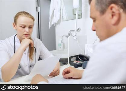 Doctor and nurse discussing analyses sitting at the table