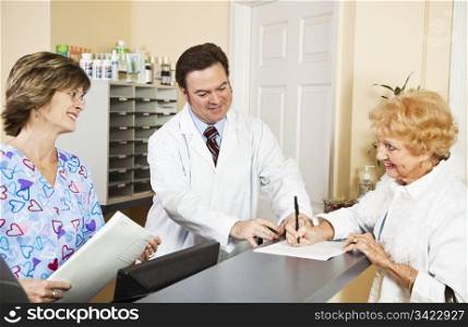 Doctor and nurse greating a new patient as she signs in. Focus on doctor.