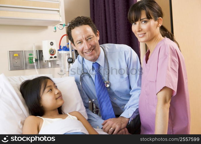 Doctor And Nurse Standing In Hospital Room With Young Girl