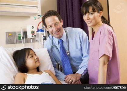Doctor And Nurse Standing In Hospital Room With Young Girl