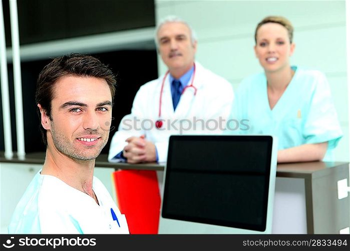 Doctor and nurses around a computer with a blank screen