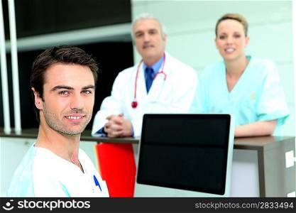 Doctor and nurses around a computer with a blank screen