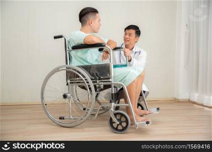 Doctor And Patient Discussing While Sitting In Wheelchair At Hospital
