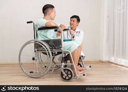Doctor And Patient Discussing While Sitting In Wheelchair At Hospital