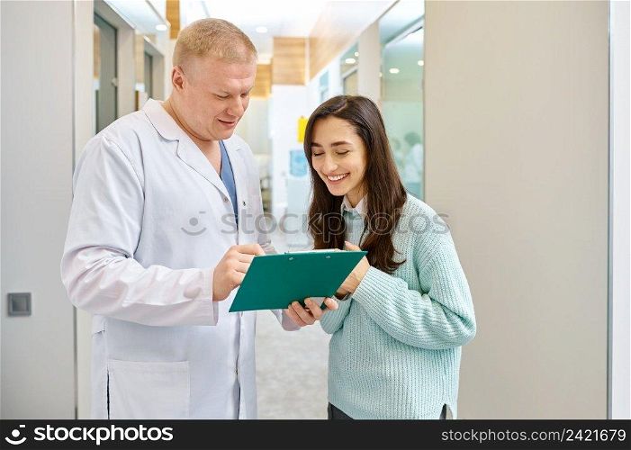 Doctor and patient looking in document on clipboard. Medical checkup results discussion. Doctor and patient discussing medical checkup results