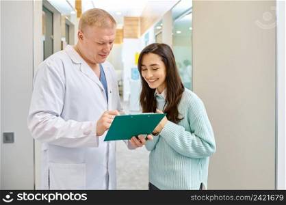 Doctor and patient looking in document on clipboard. Medical checkup results discussion. Doctor and patient discussing medical checkup results