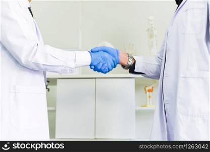 Doctor and scientist shaking hands with her colleague healthcare and cooperation or the success of the research trial scientific concept / Male scientist are shaking hand in laboratory