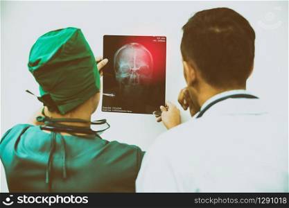 Doctor and surgeon examining x-ray film of patient &rsquo;s head for brain, skull or eye injury. Medical diagnosis and surgical treatment concept.