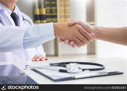 doctor at the clinic giving an handshake to his patient for encouragement and empathy, healthcare and assistance concept