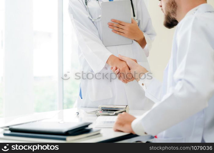 Doctor at the hospital giving handshake to another doctor showing success and teamwork of professional healthcare staff.