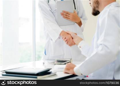 Doctor at the hospital giving handshake to another doctor showing success and teamwork of professional healthcare staff.