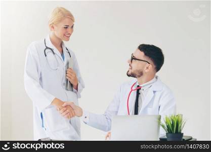 Doctor at the hospital giving handshake to another doctor showing success and teamwork of professional healthcare staff.. Doctor at hospital shakes hand with another doctor
