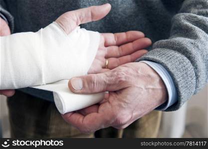 Doctor, bandaging a strained wrist of a patient with a swathing band