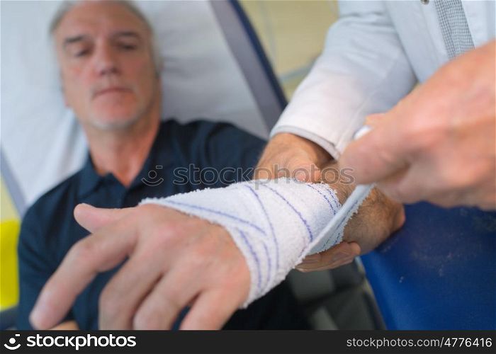 doctor bandaging his patient hand in medical office
