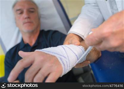 doctor bandaging his patient hand in medical office