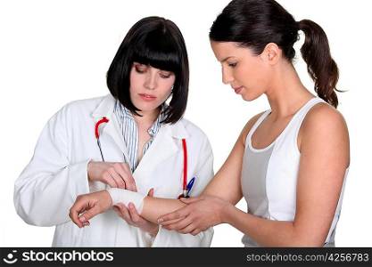 Doctor bandaging patient&acute;s wrist