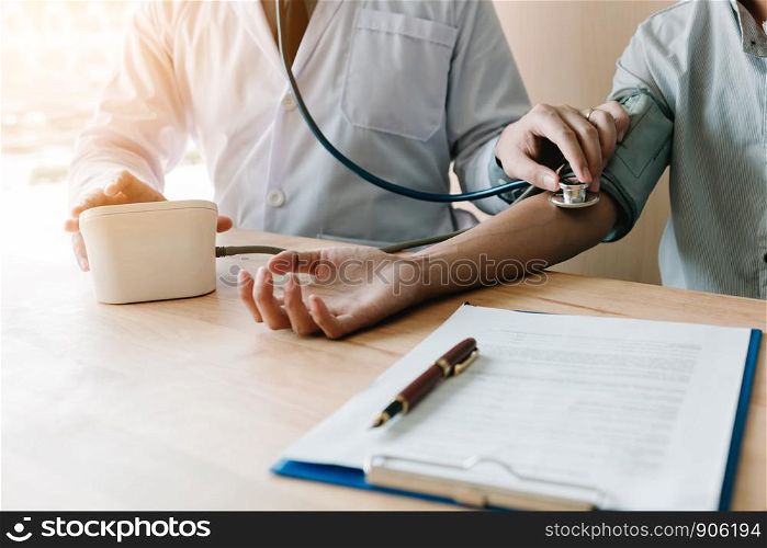 Doctor checking a senior patient's blood pressure in office room.