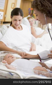 Doctor checking baby&acute;s heartbeat with new mother watching and smiling