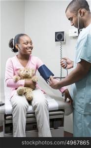 Doctor checking girls blood pressure