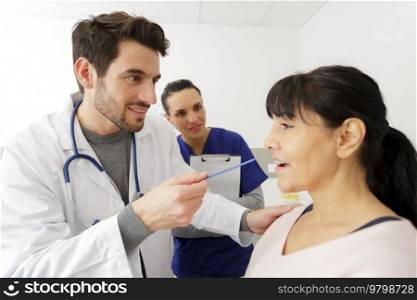 doctor checking inside the mouth of a mature female patient