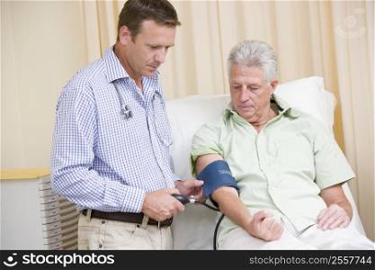 Doctor checking man&acute;s blood pressure in exam room