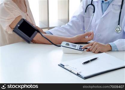 Doctor checking mature patient blood pressure