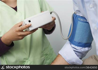 Doctor checking patients blood pressure,close-up