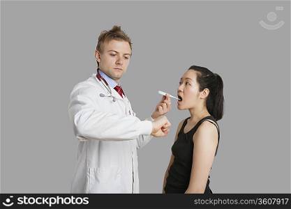 Doctor checking temperature of female patient