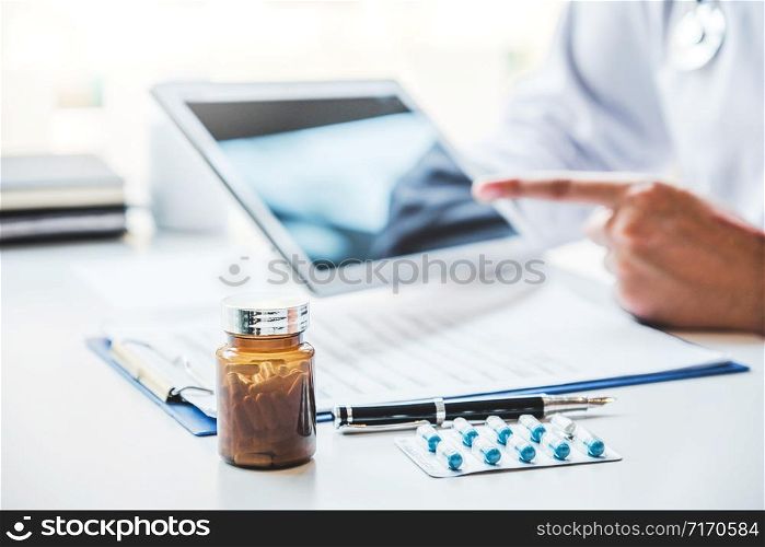 Doctor consulting with patient presenting results on digital tablet tablet sitting at table
