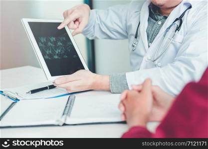 Doctor consulting with patient presenting results x-ray film on digital tablet About the problem of the patient