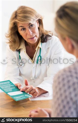 Doctor Discussing Leaflet With Female Patient