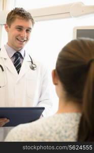 Doctor discussing medical chart with a patient sitting on a hospital bed