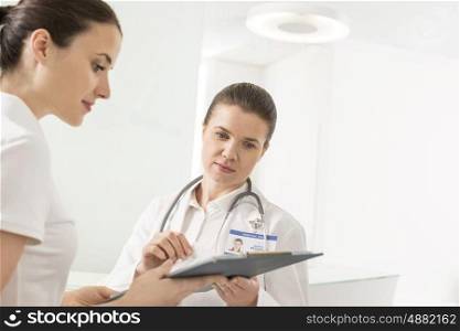 Doctor discussing with assistant on documents at hospital