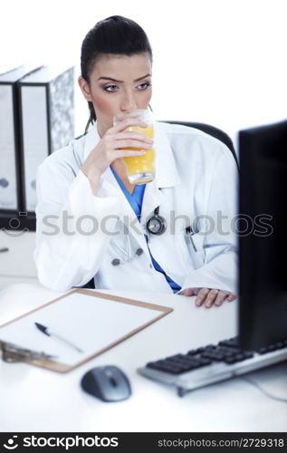 Doctor drinking a glass of juice at her workplace over white background