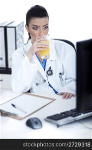 Doctor drinking a glass of juice at her workplace over white background