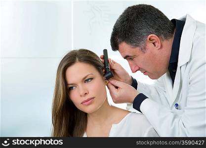 Doctor ENT checking ear with otoscope to woman patient at hospital