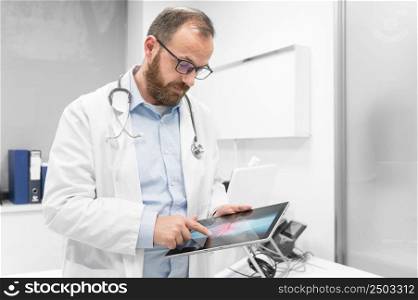 Doctor examine an x-ray image of a patient in digital tablet at doctor office. High quality photography.. Doctor examine an x-ray image of a patient in digital tablet at doctor office.