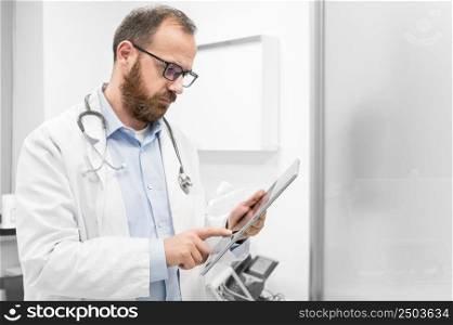 Doctor examine an x-ray image of a patient in digital tablet at doctor office. High quality photography.. Doctor examine an x-ray image of a patient in digital tablet at doctor office.