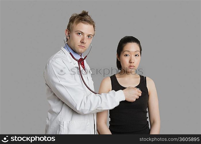Doctor examining female patient with stethoscope