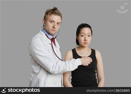 Doctor examining female patient with stethoscope