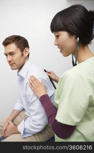 Doctor examining male patient using stethoscope in hospital