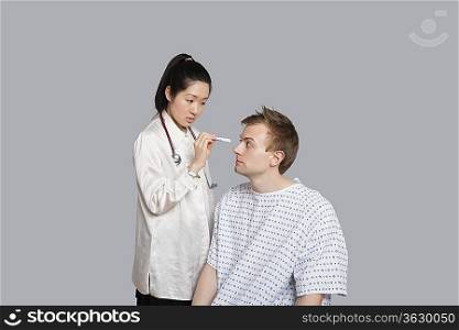Doctor examining patient&acute;s eye with flashlight