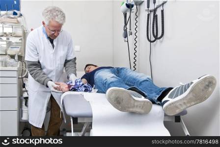 Doctor examining the injured hand of a patient in a medical emergency post