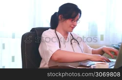 Doctor examining X-Ray Films writing results on laptop computer