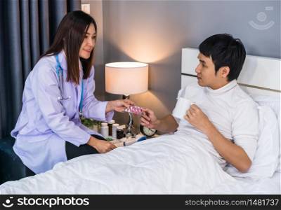 Doctor explaining the pills to male patient in a bed