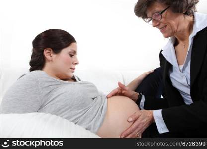 Doctor feeling a woman&rsquo;s pregnant stomach