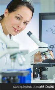 Doctor, female medical or scientific researcher using her microscope in a laboratory.