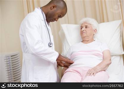 Doctor giving checkup to woman in exam room